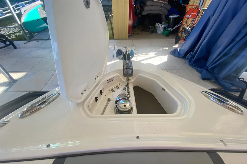 Slide: The Image of 2018 Chaparral 337 SSX boat anchor compartment with open hatch in a marina setting. - 39
