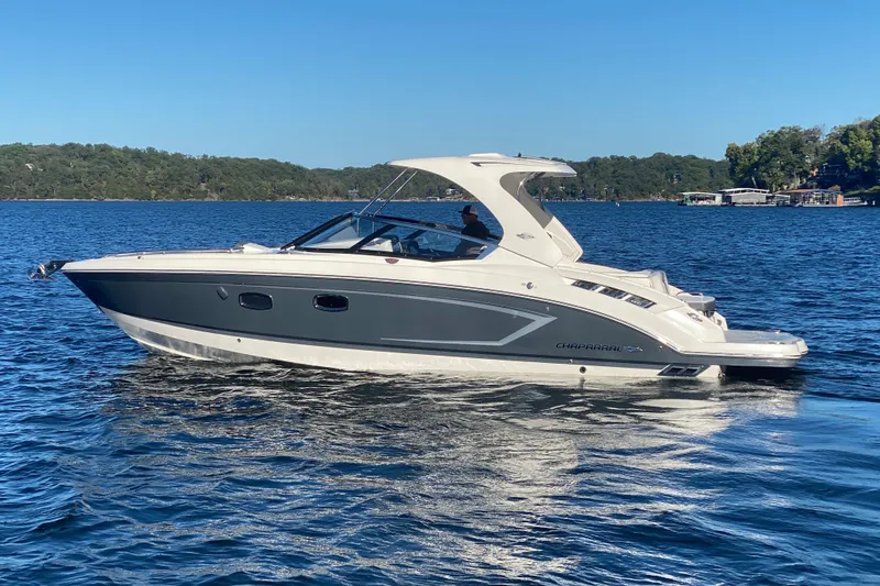 Slide: The Image of 2018 Chaparral 337 SSX boat cruising on a serene lake under a clear blue sky. - 54