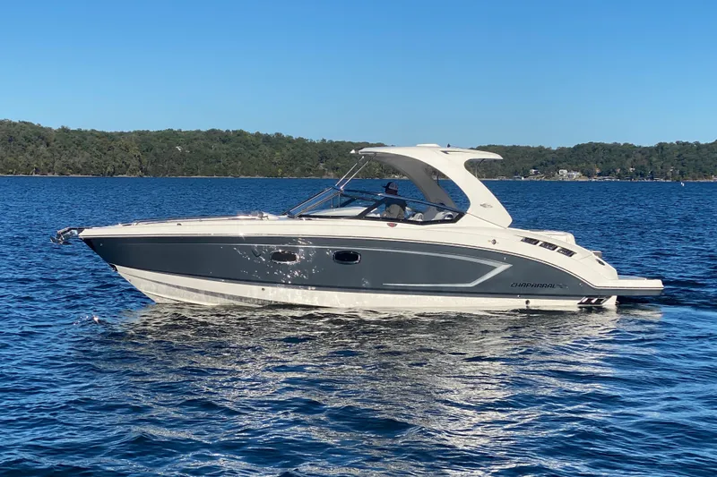 Slide: The Image of 2018 Chaparral 337 SSX boat cruising on a serene lake under clear blue skies. - 55