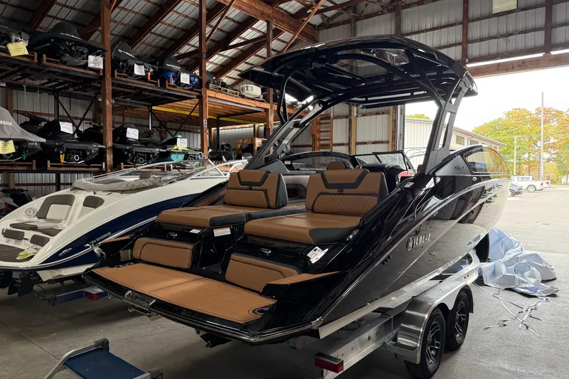 The Image of 2026 Yamaha Boats 275SD in a warehouse, showcasing sleek design and luxurious seating. - 0