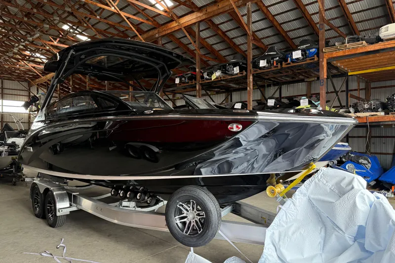 Slide: The Image of 2026 Yamaha Boats 275SD in storage, sleek black design, on trailer in warehouse. - 1