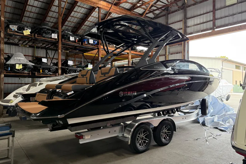Slide: The Image of 2026 Yamaha Boats 275SD in storage, sleek black design on a trailer. - 12