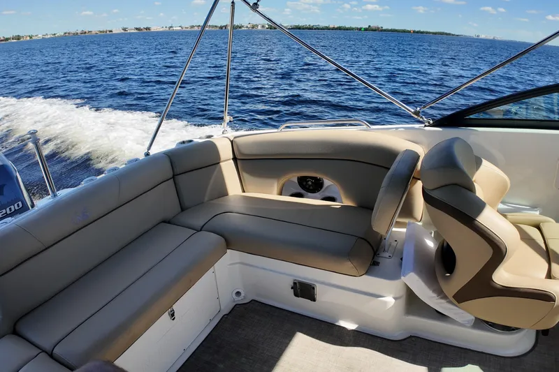 Slide: The Image of 2020 NauticStar 243 DC boat interior with beige seating, cruising on open water. - 11