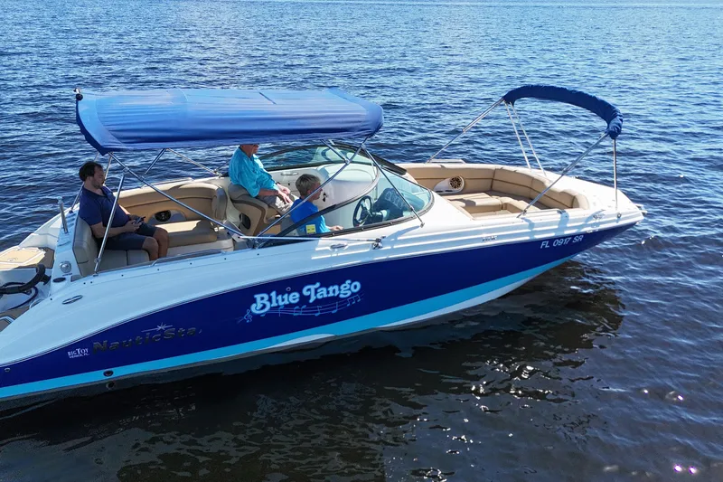 Slide: The Image of 2020 NauticStar 243 DC boat named "Blue Tango" on water with passengers. - 14