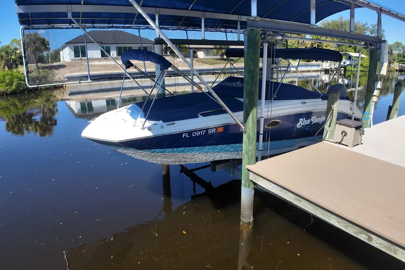 Slide: The Image of 2020 NauticStar 243 DC boat docked under a blue canopy on calm water. - 15