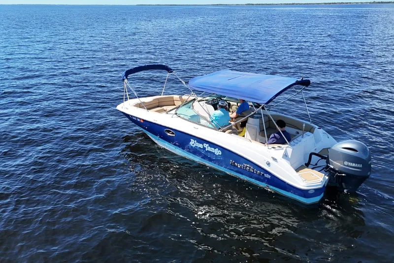 Slide: The Image of 2020 NauticStar 243 DC boat cruising on open water with blue canopy. - 2