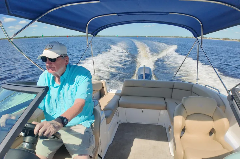 Slide: The Image of Man steering 2020 NauticStar 243 DC boat on open water under blue sky. - 5