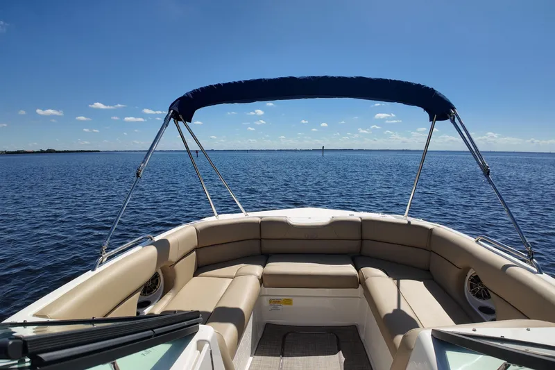 Slide: The Image of 2020 NauticStar 243 DC boat with beige seating, blue canopy, on open water. - 6