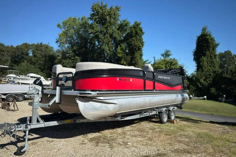 The Image of 2024 Premier 250 Solaris pontoon boat on trailer, parked outdoors. - 0