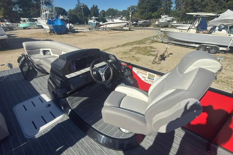 Slide: The Image of 2024 Premier 250 Solaris boat interior with steering wheel and seating, docked among other boats. - 4