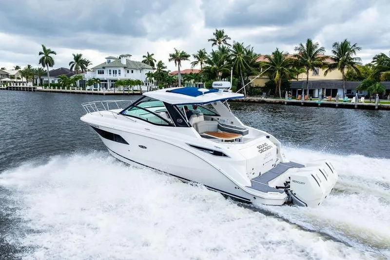 Slide: The Image of 2021 Sea Ray Sundancer 320 Outboard cruising on a scenic waterway with palm trees. - 10