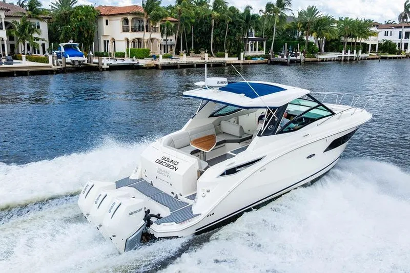 Slide: The Image of 2021 Sea Ray Sundancer 320 Outboard cruising on a scenic waterway with luxury homes. - 13