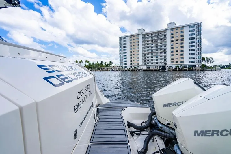 Slide: The Image of 2021 Sea Ray Sundancer 320 Outboard on water, with building and cloudy sky backdrop. - 32