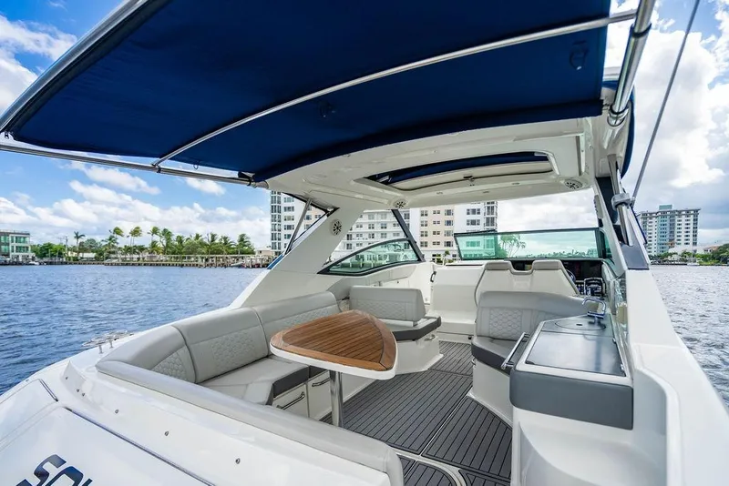 Slide: The Image of 2021 Sea Ray Sundancer 320 Outboard interior with seating, table, and waterfront view. - 49