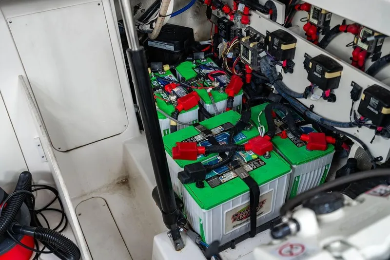 Slide: The Image of 2021 Sea Ray Sundancer 320 Outboard battery compartment with multiple green batteries and wiring. - 53