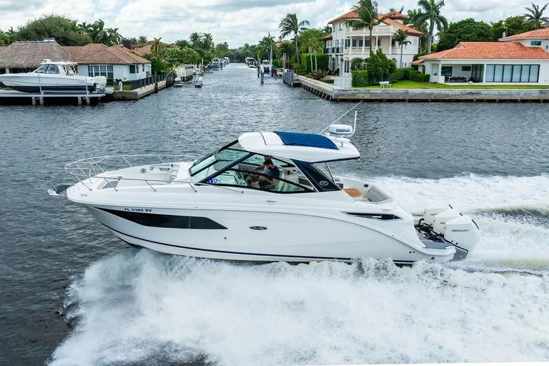 Slide: The Image of 2021 Sea Ray Sundancer 320 Outboard cruising on a scenic waterway near luxury homes. - 8