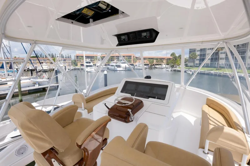 Slide: The Image of Interior view of 2017 Viking 48 Convertible yacht's helm with beige seating and marina backdrop. - 1