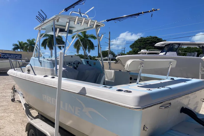 Slide: The Image of 1997 Pro-Line 255 boat with T-top and fishing rod holders, parked on a trailer. - 3