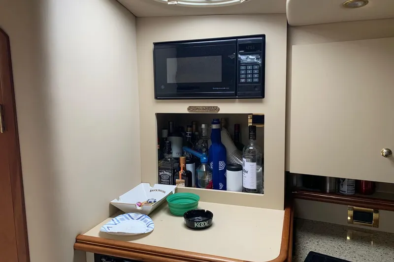Slide: The Image of 2002 Cruisers 3275 Express cabin with microwave and bar area, featuring various bottles and accessories. - 24