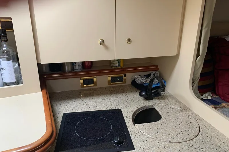 Slide: The Image of 2002 Cruisers 3275 Express yacht kitchenette with stove, sink, and storage cabinets. - 23