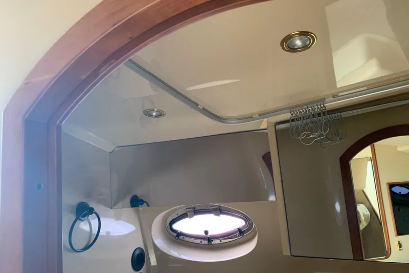 Slide: The Image of Interior of 2002 Cruisers 3275 Express boat, featuring a porthole and wooden trim. - 33