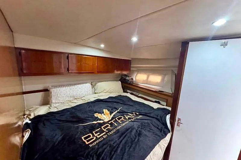 Slide: The Image of Cozy bedroom in a 1973 Bertram 46.6 yacht with branded bedding and wooden cabinets. - 23