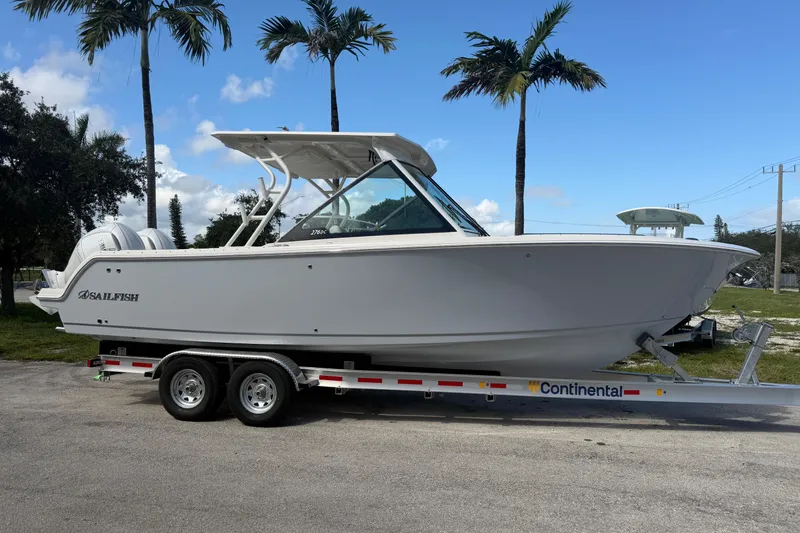 The Image of 2026 Sailfish 276 DC boat on trailer, parked under palm trees. - 0