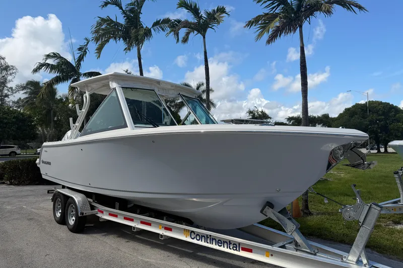 Slide: The Image of 2026 Sailfish 276 DC boat on trailer, surrounded by palm trees and blue sky. - 1