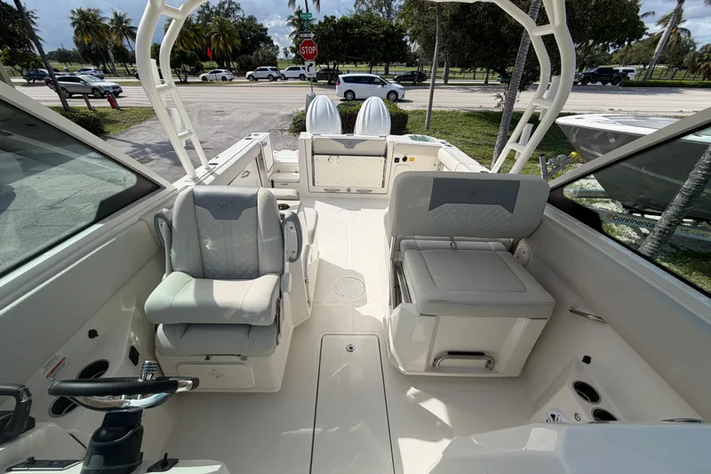 Slide: The Image of 2026 Sailfish 276 DC boat interior with seating and steering wheel, parked near a road. - 16