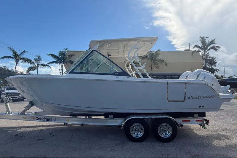 Slide: The Image of 2026 Sailfish 276 DC boat on trailer, parked outdoors with palm trees in background. - 3