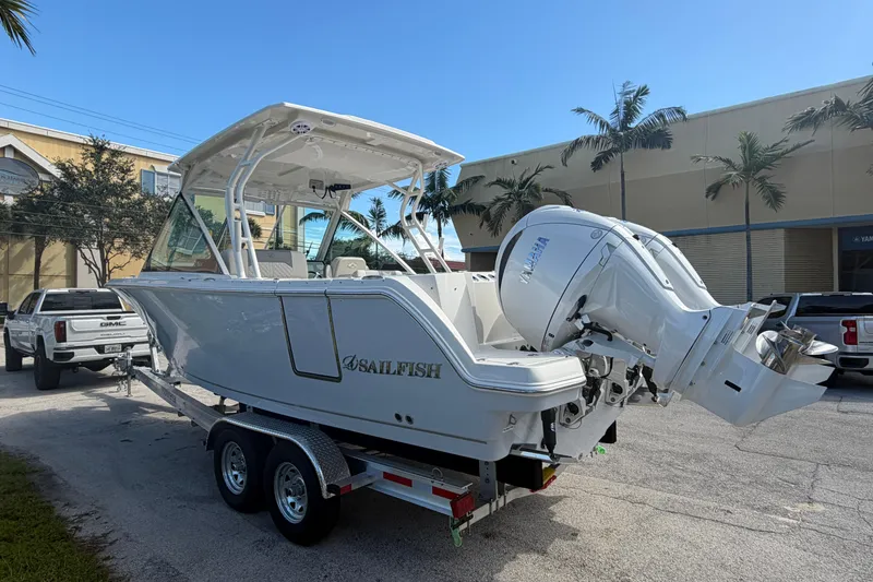 Slide: The Image of 2026 Sailfish 276 DC boat on trailer, parked outdoors with palm trees in background. - 5
