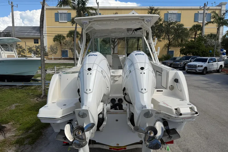 Slide: The Image of 2026 Sailfish 276 DC boat with dual outboard engines, parked outdoors. - 7