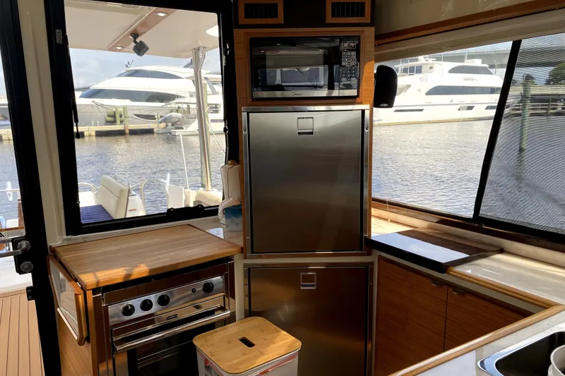 Slide: The Image of Interior of 2022 Ranger Tugs 43-CB yacht kitchen with appliances and marina view. - 25