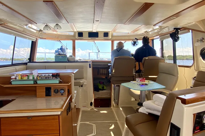 Slide: The Image of Interior of 2022 Ranger Tugs 43-CB boat with passengers, featuring a cozy seating area. - 32