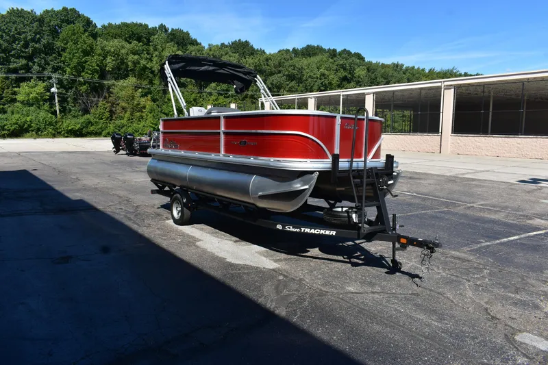 Slide: The Image of 2026 Sun Tracker Party Barge 18 DLX pontoon boat on trailer, parked outdoors. - 4