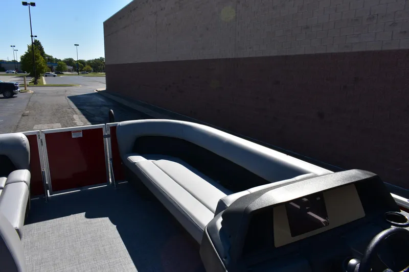 Slide: The Image of 2026 Sun Tracker Party Barge 18 DLX interior with seating and console, parked outdoors. - 67