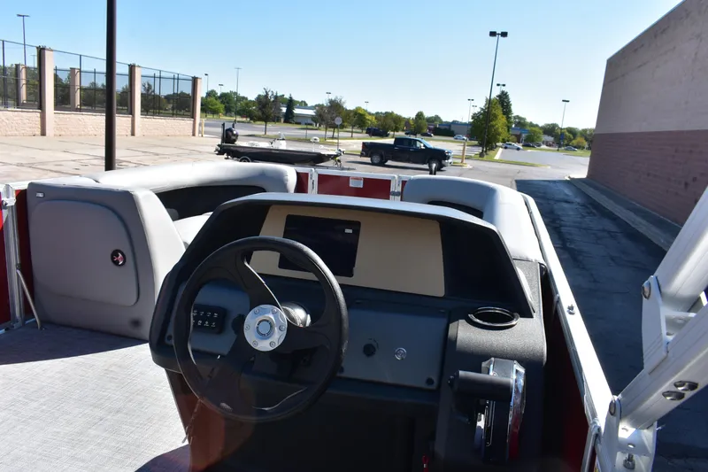 Slide: The Image of 2026 Sun Tracker Party Barge 18 DLX interior with steering wheel and seating in a parking lot. - 80