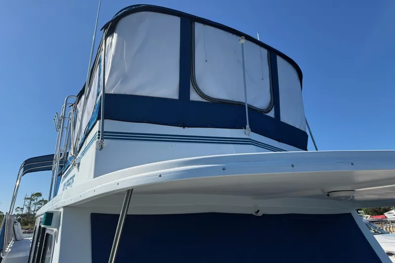Slide: The Image of 1996 Harbor Master 52 Wide Body boat with blue and white canopy under clear sky. - 10