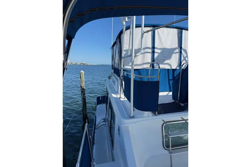 Slide: The Image of 1996 Harbor Master 52 Wide Body boat docked on calm water under clear blue sky. - 4