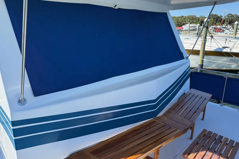 Slide: The Image of 1996 Harbor Master 52 Wide Body boat with blue awning and wooden seating on deck. - 8