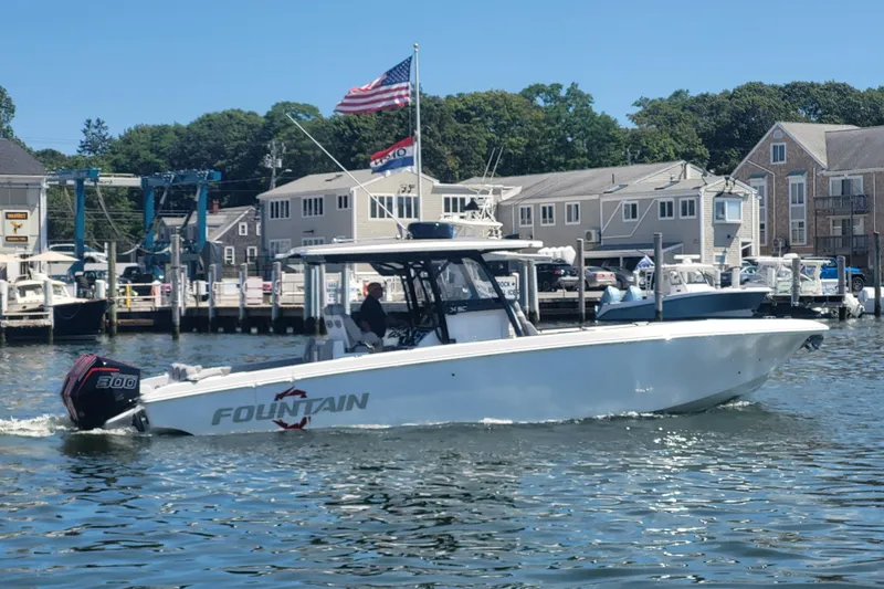 The Image of 2025 Fountain 34 SC boat cruising in a marina with American flag. - 0