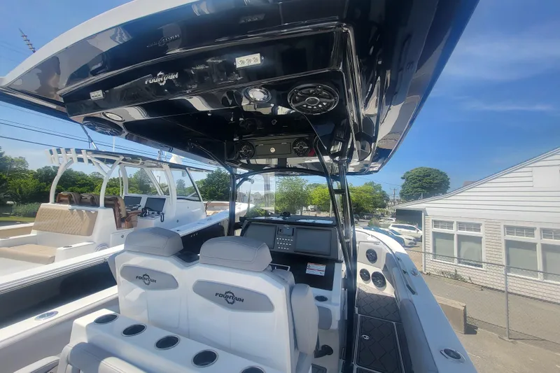 Slide: The Image of 2025 Fountain 34 SC boat interior with modern dashboard and seating under a clear blue sky. - 12