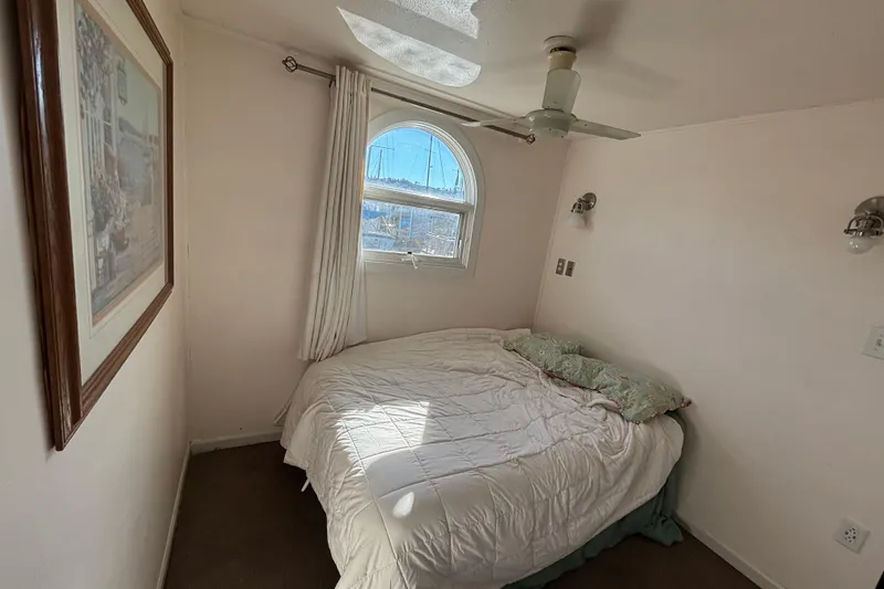 Slide: The Image of Cozy bedroom in 2004 River Floating Home with window, ceiling fan, and wall art. - 6