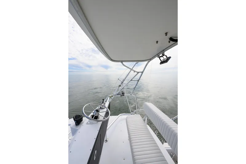 Slide: The Image of 1998 Bertram 36 Moppie boat helm with ocean view, featuring steering wheel and seating. - 22