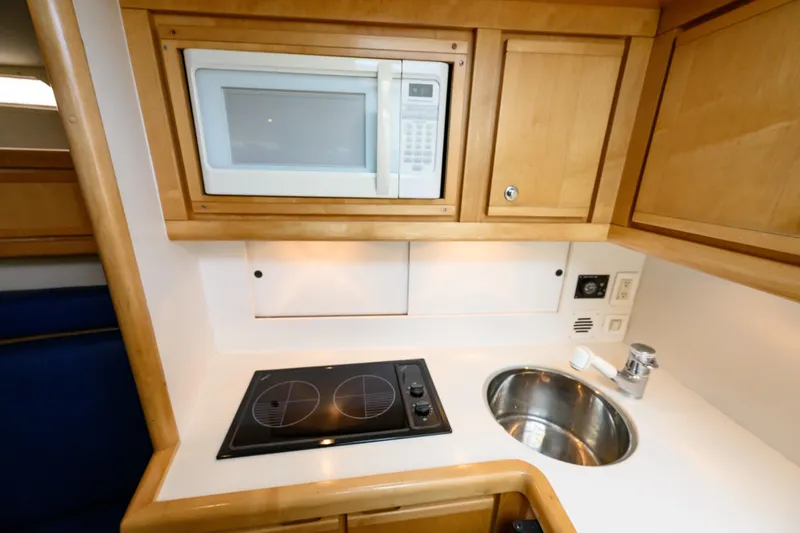 Slide: The Image of Compact kitchen area in a 1998 Bertram 36 Moppie yacht with microwave and stovetop. - 27