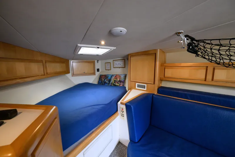 Slide: The Image of Interior cabin of a 1998 Bertram 36 Moppie with blue bedding and wooden cabinets. - 31