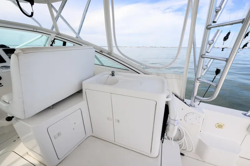 Slide: The Image of 1998 Bertram 36 Moppie boat interior with white seating and sink, overlooking calm waters. - 7