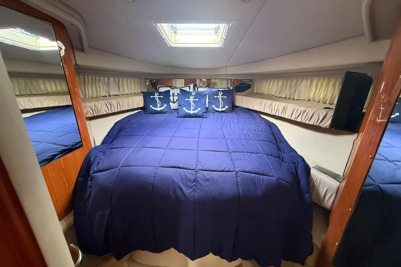 Slide: The Image of 2001 Sea Ray 410 Sundancer cabin with blue bedding and anchor-themed pillows. - 12
