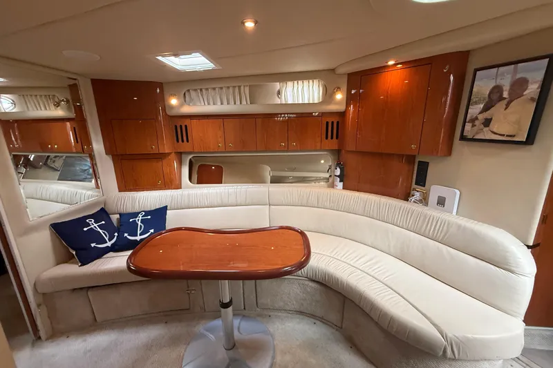 Slide: The Image of Luxurious interior of 2001 Sea Ray 410 Sundancer yacht with curved seating and wooden table. - 9