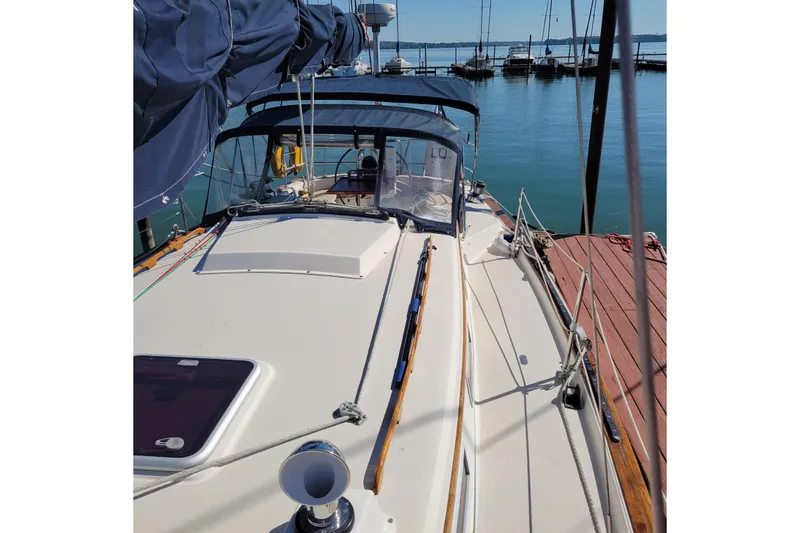 Slide: The Image of 1984 Pearson 386 sailboat docked at marina, featuring a spacious deck and blue canopy. - 11